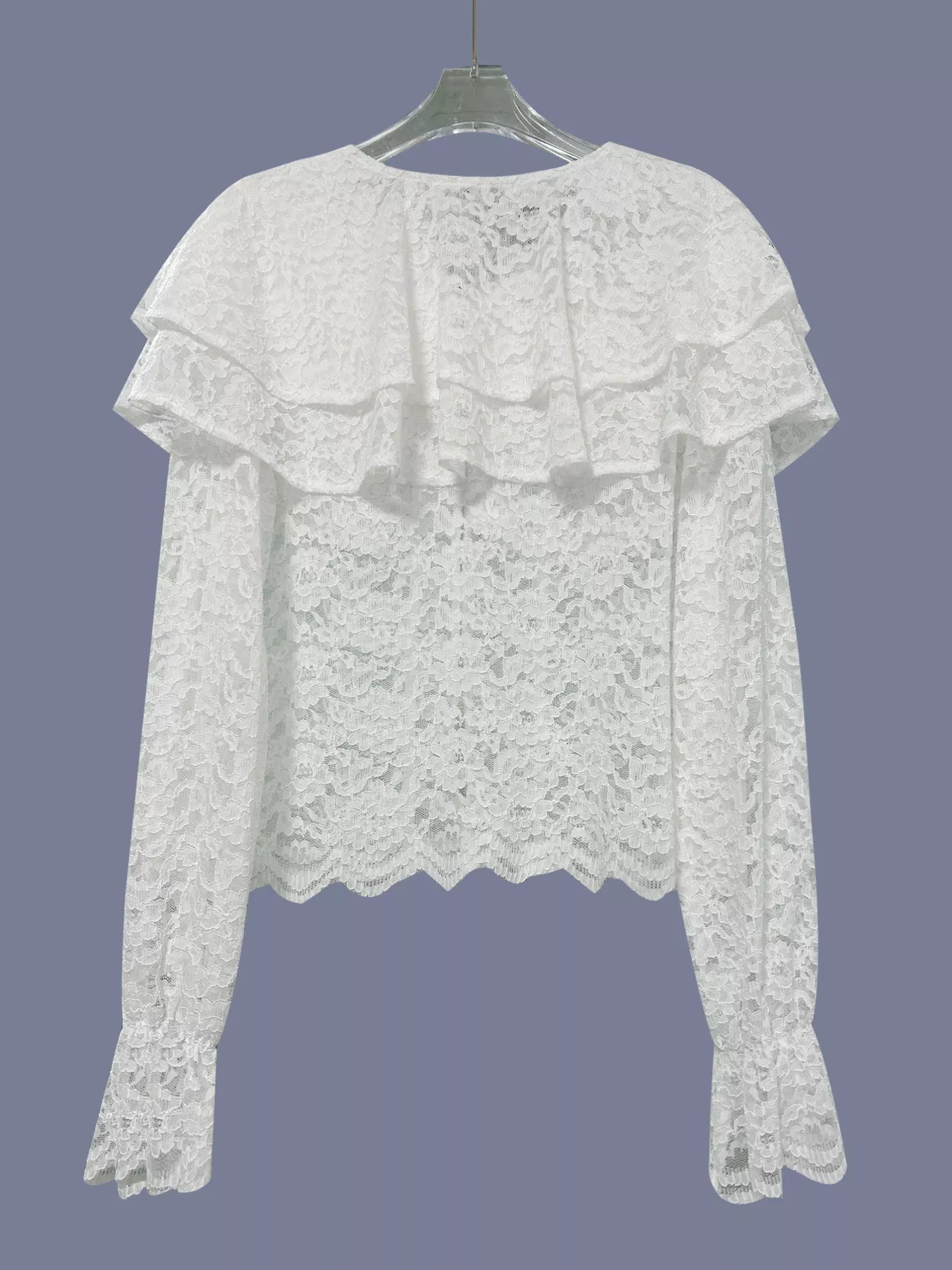 White lace blouse on a hanger against a gray background