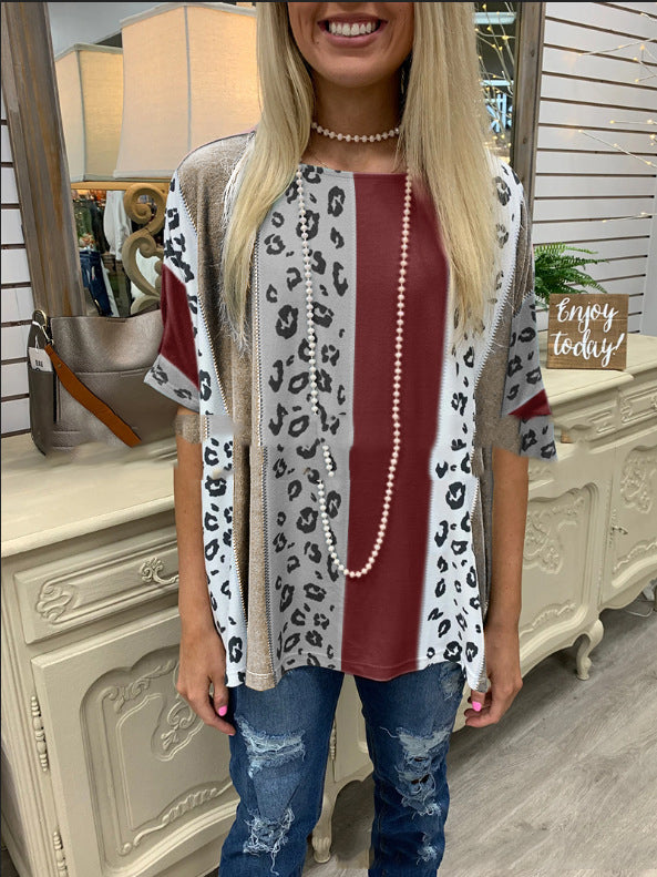 Woman wearing a leopard print cardigan over a red top with blue jeans indoors.