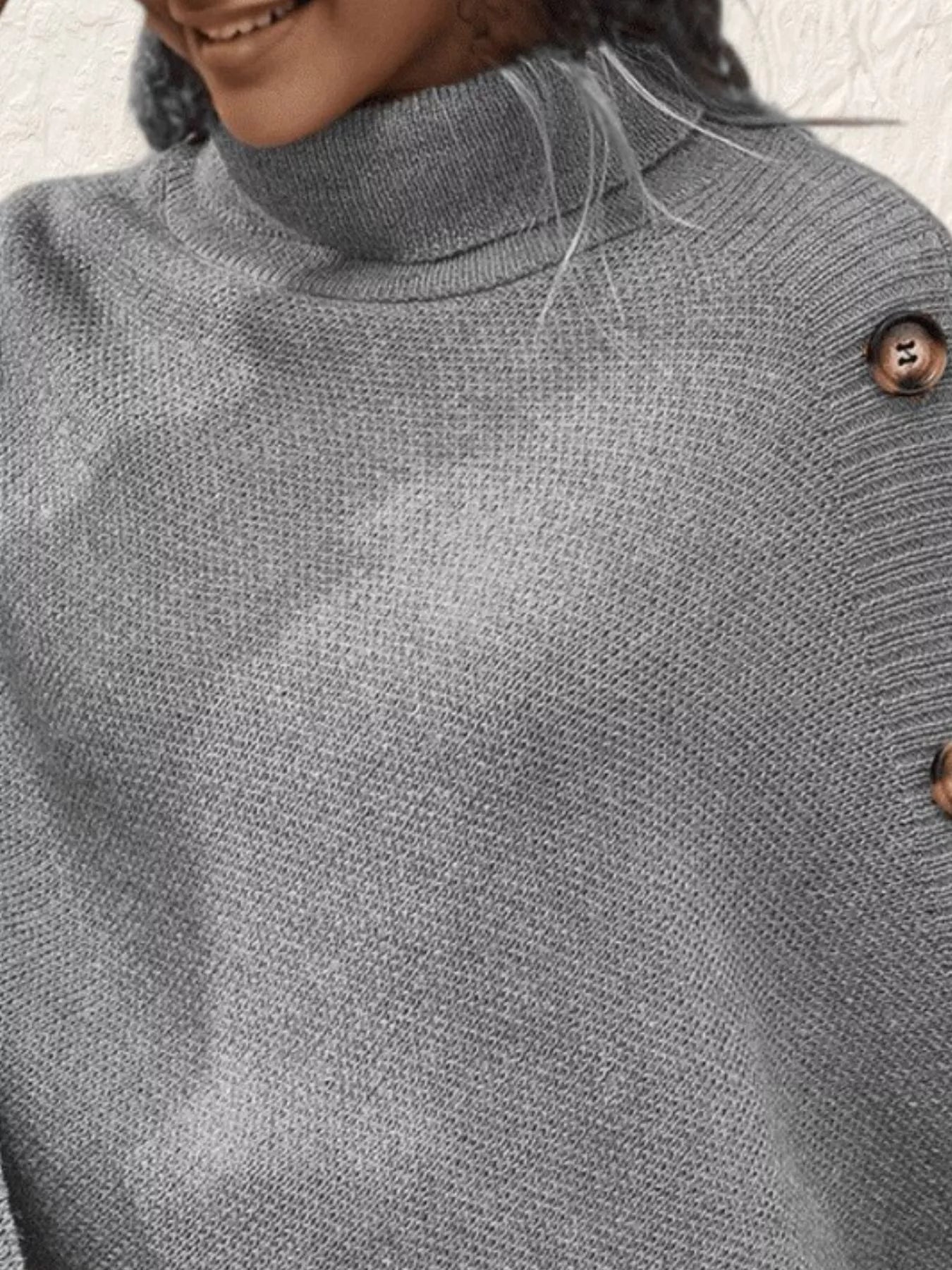 Close-up of a gray sweater with a button detail