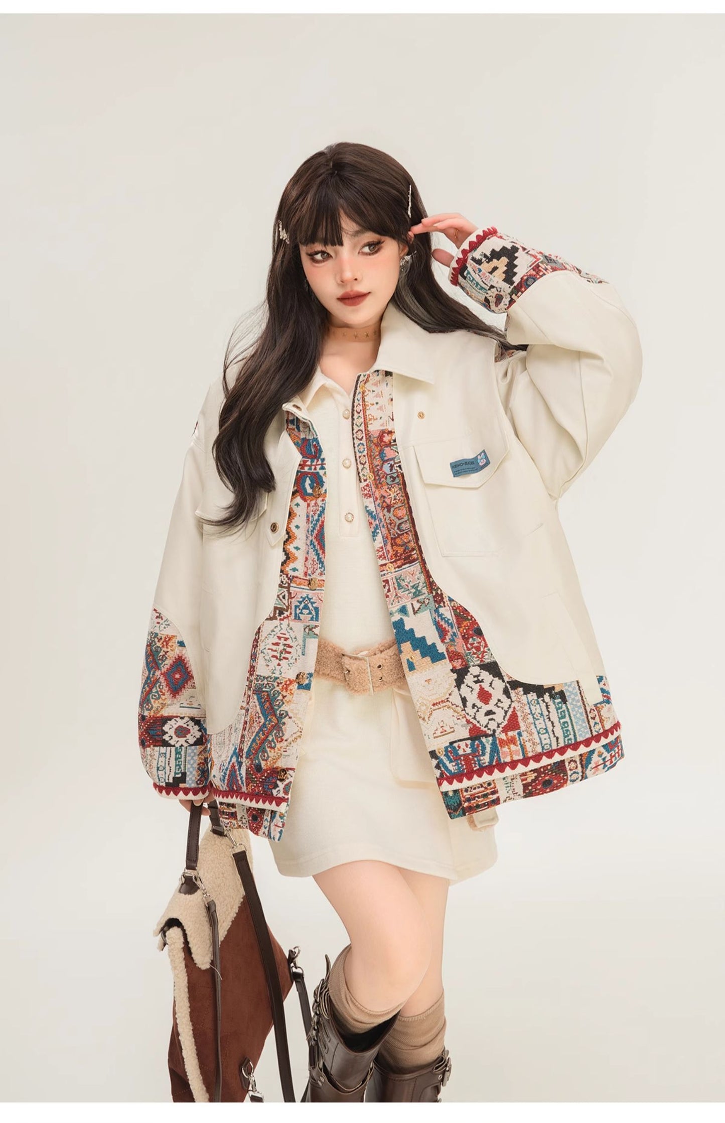 Person wearing a patterned jacket over a white outfit with a white background