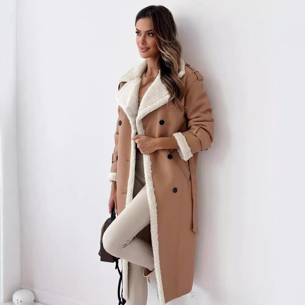 Woman wearing a tan coat with white fur lining against a white wall