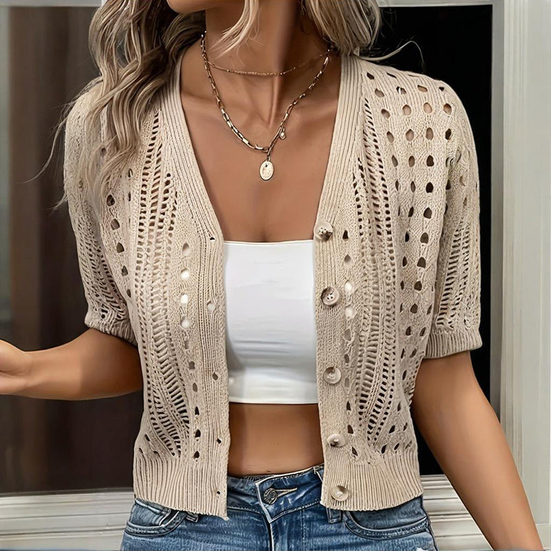 Woman wearing a beige knit cardigan layered over a white crop top, styled with casual denim for a minimalist 2026 fashion look