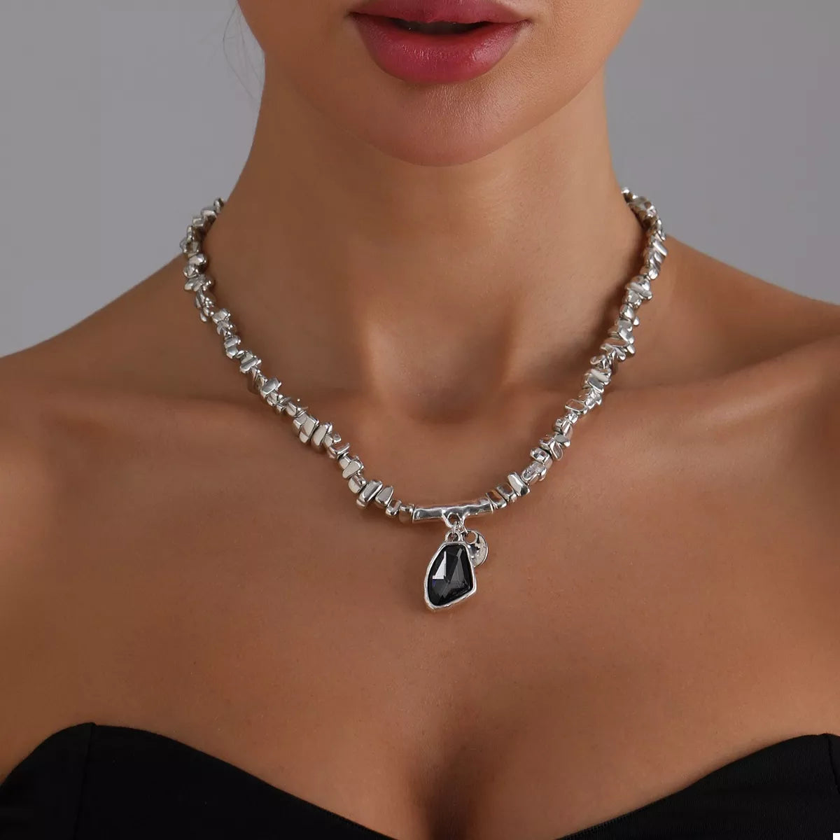 Necklace with a black pendant worn by a model against a neutral background