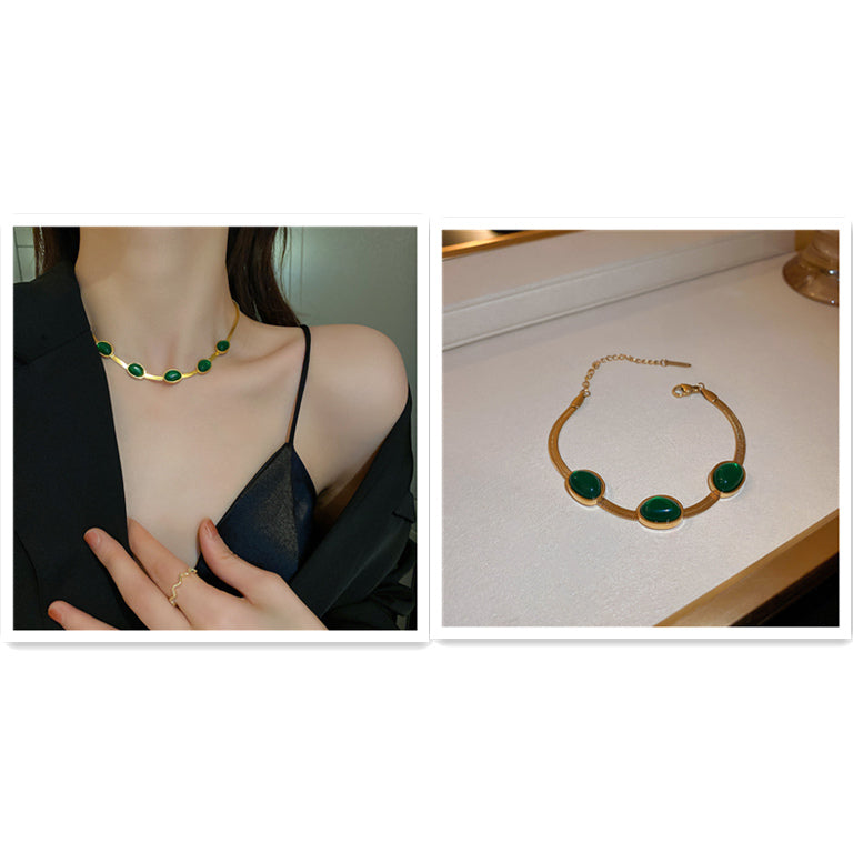 Gold necklace with green stones worn by a person and displayed on a table.