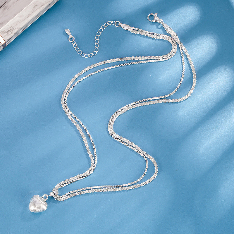 Silver necklace with a heart-shaped pendant on a blue background