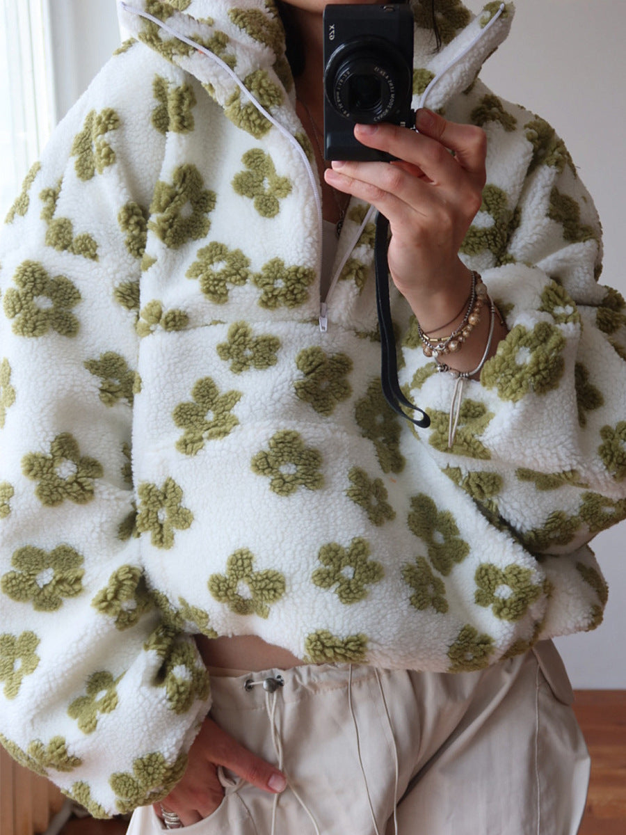 Person wearing a white fleece jacket with green floral patterns, holding a camera.