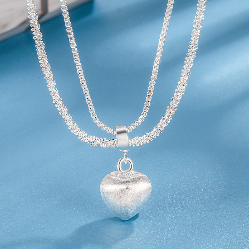 Silver heart-shaped pendant necklace on a blue background