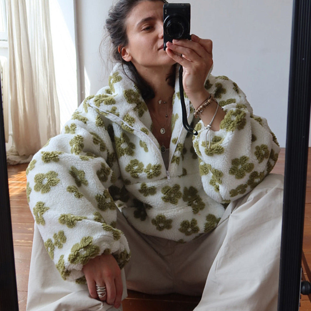 Woman taking a mirror selfie wearing a white fleece jacket with green floral patterns.