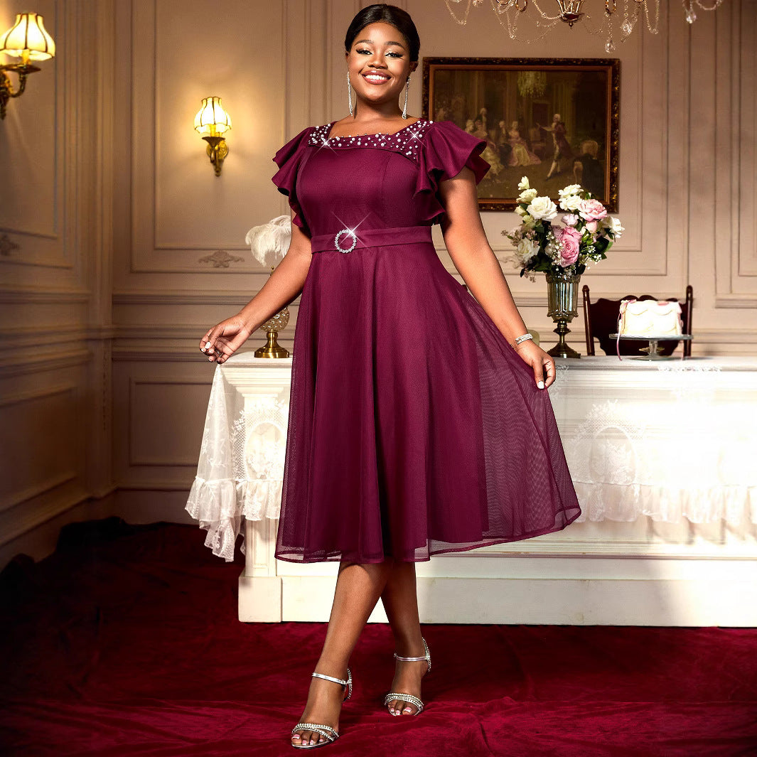 Woman in a purple dress standing in an elegant room with floral arrangements.