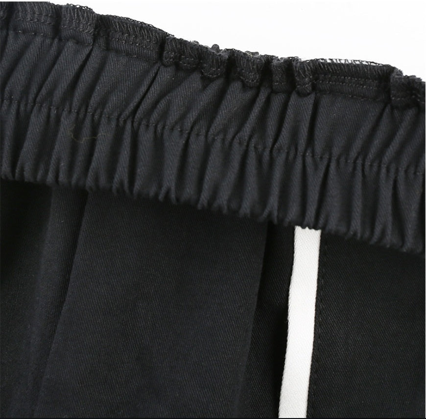 Close-up of black off-shoulder top with ruffled neckline on a white background