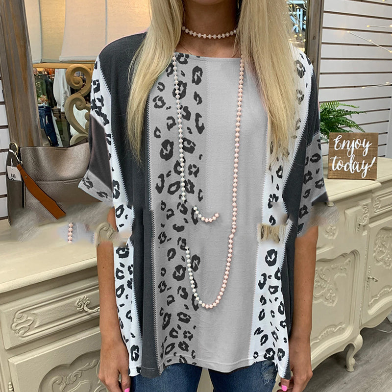 Woman wearing a leopard print cardigan over a gray top with a pearl necklace, standing in a decorated room.