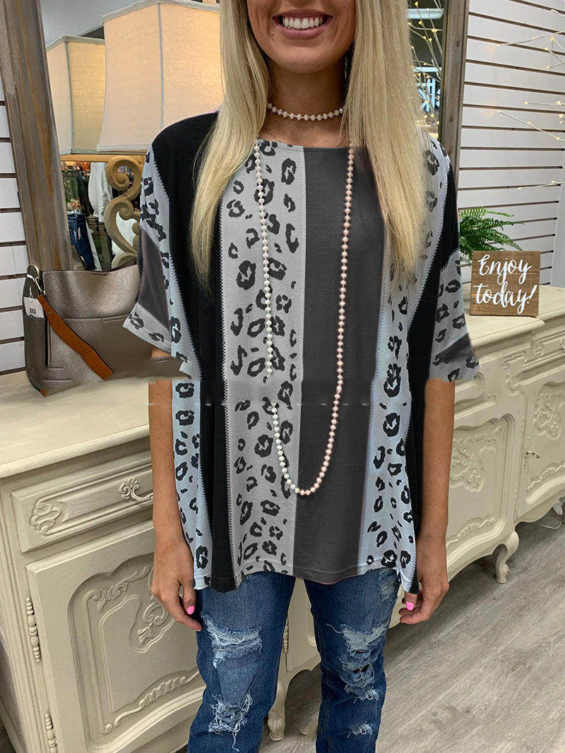 Woman wearing a leopard print cardigan over a gray top with blue jeans, standing indoors.