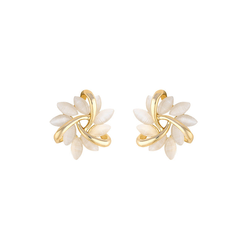 Pair of gold and white floral earrings on a white background