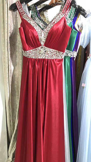 Red evening gown with beaded details on a hanger against a curtain background