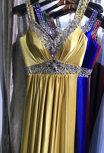 Gold evening gown with beaded details on a hanger