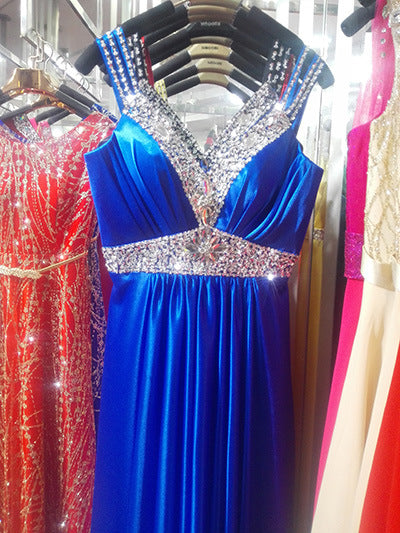 Blue evening gown with sparkling embellishments on a rack with other dresses.