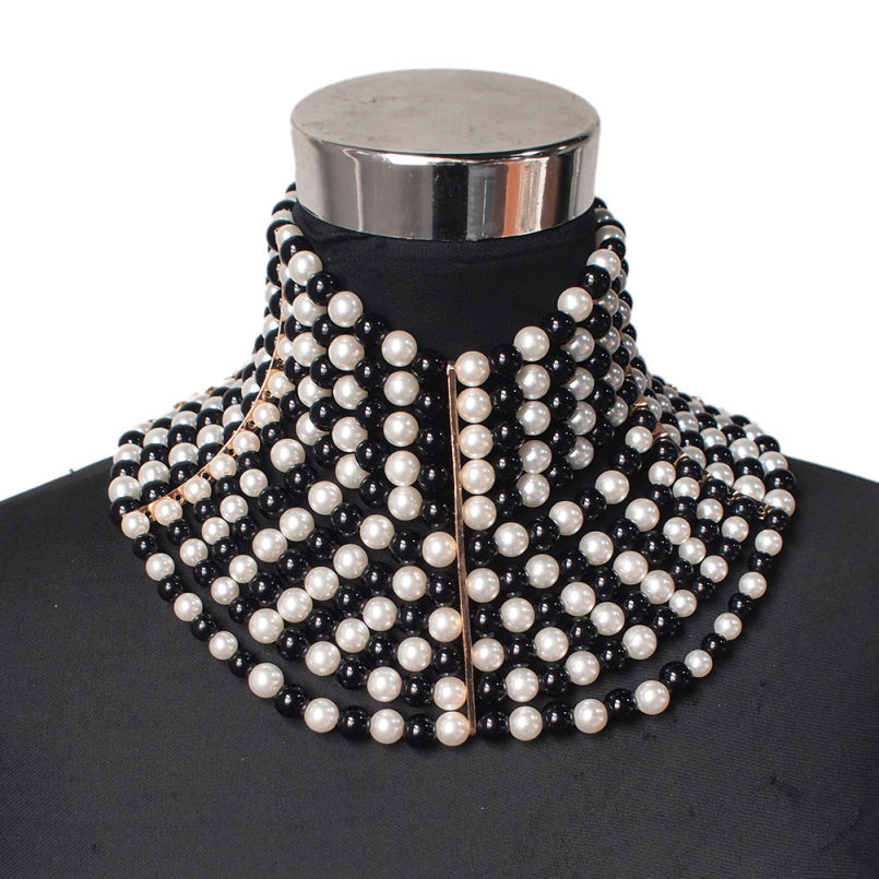 Black and white pearl necklace on a mannequin neck with a white background
