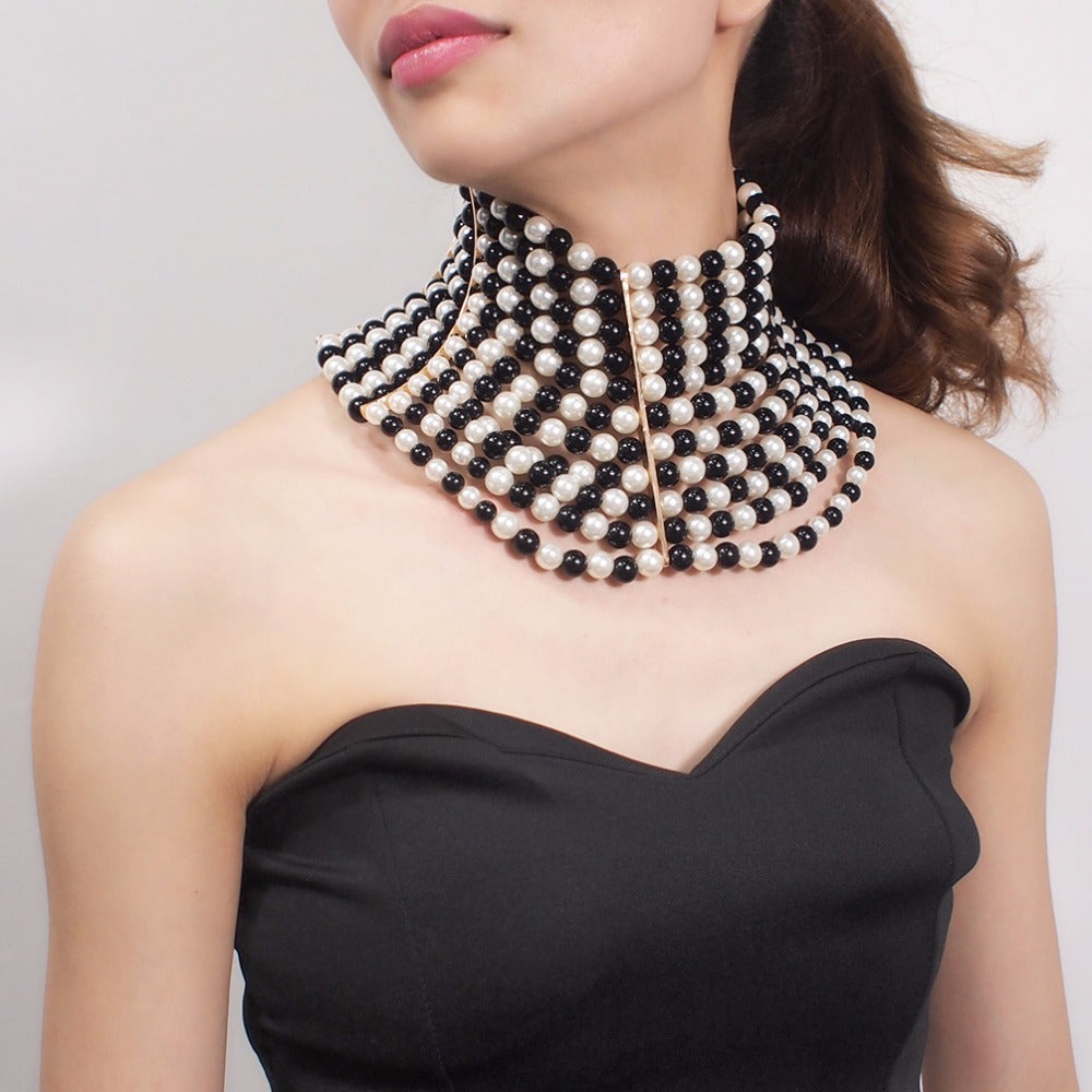 Woman wearing a black and white beaded necklace against a plain background