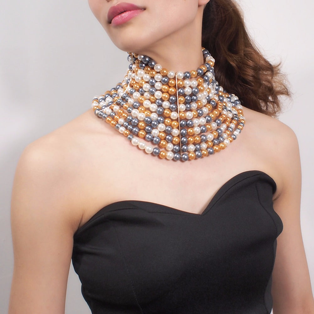 Woman wearing a multi-layered beaded necklace against a plain background
