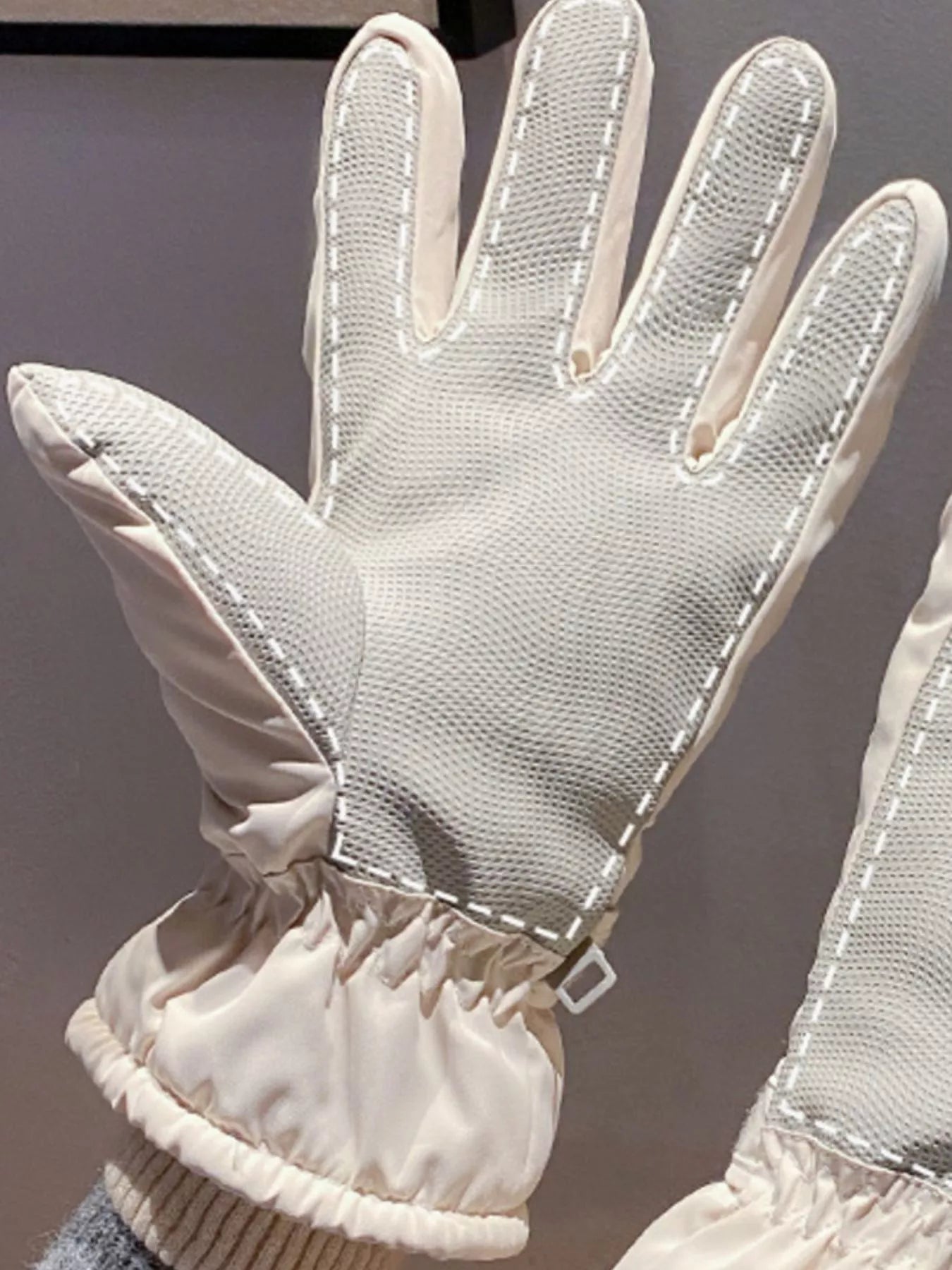 Close-up of a white glove with mesh design on a gray background