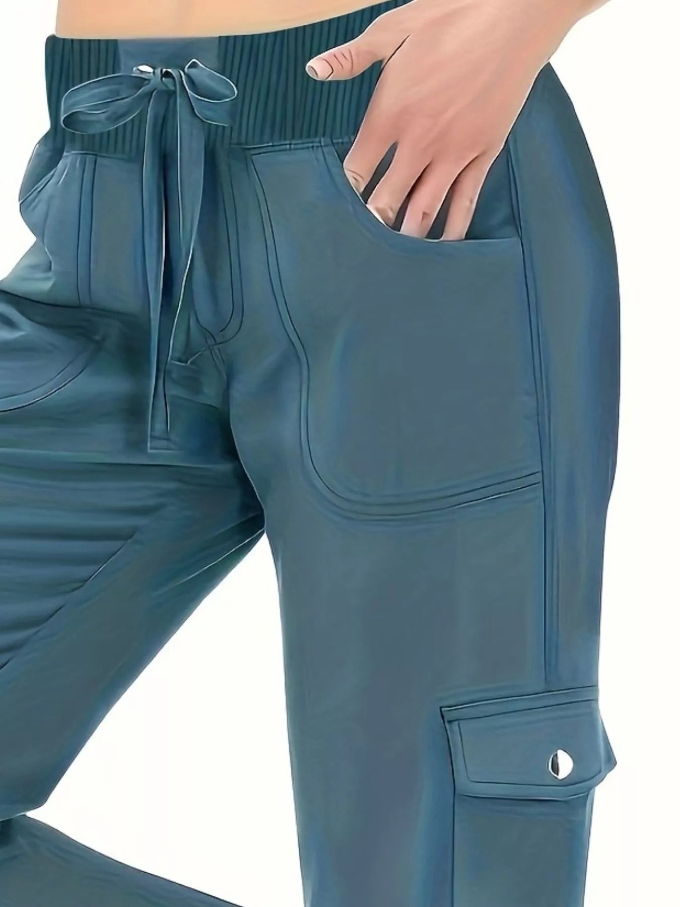 Teal jogger pants with a pocket detail on a white background