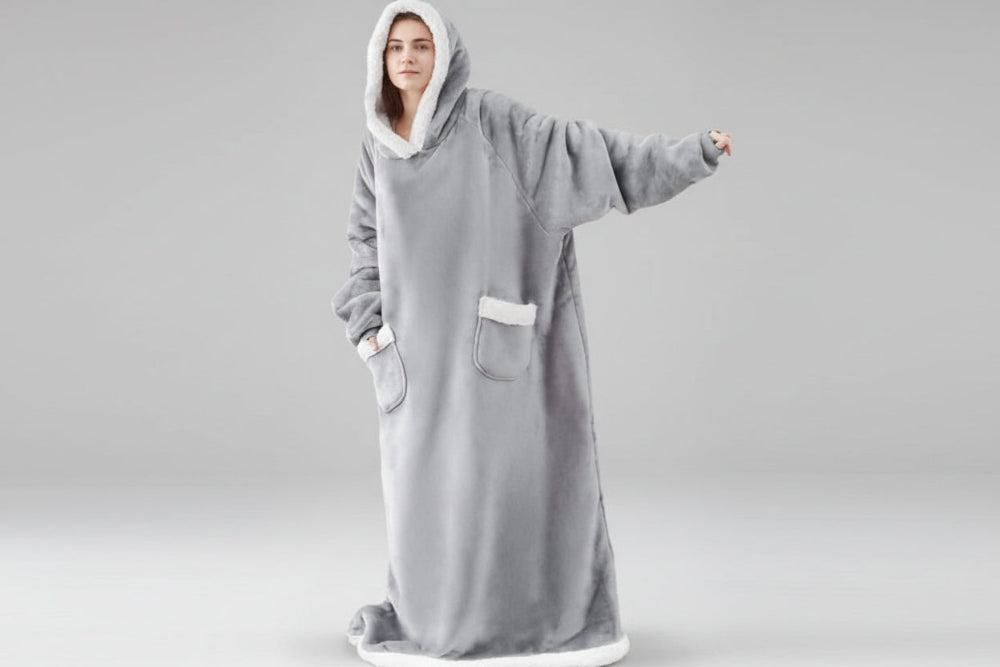 Person wearing a gray hooded blanket with white trim on a white background