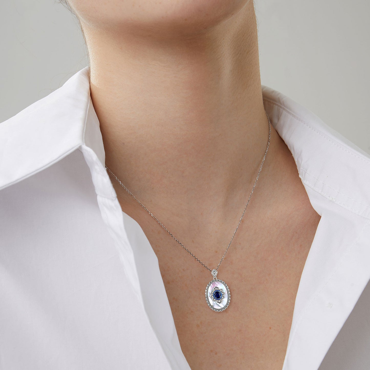 Necklace with a pendant worn by a person in a white shirt against a neutral background