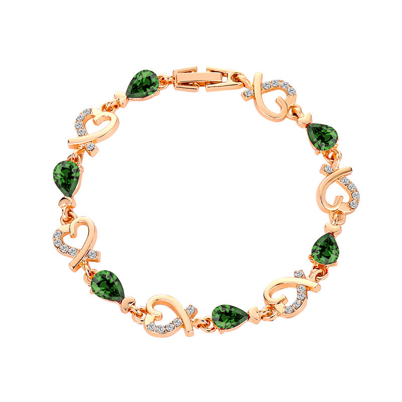Rose gold bracelet with green gemstones on a white background
