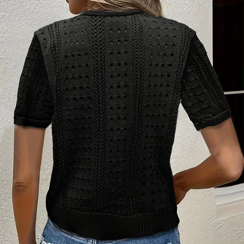 Black knitted top worn by a person against a neutral background