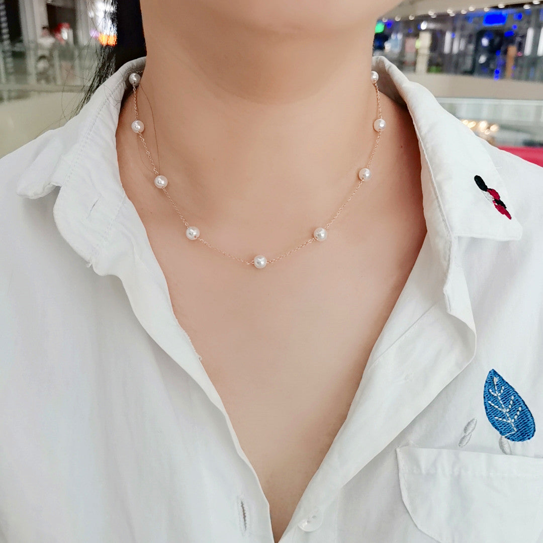 Pearl necklace worn by a person with a blurred indoor background