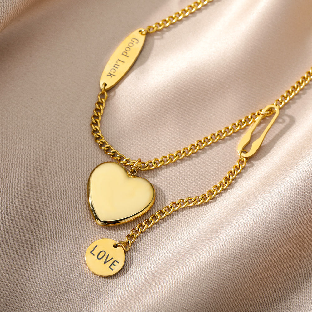 Gold necklace with heart pendant and 'LOVE' tag on a beige fabric background
