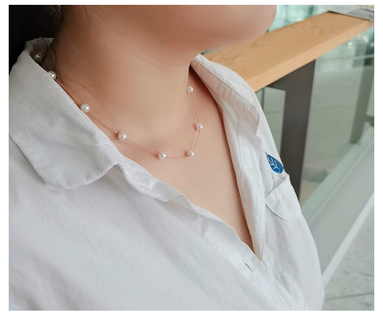Person wearing a pearl necklace with a blurred background