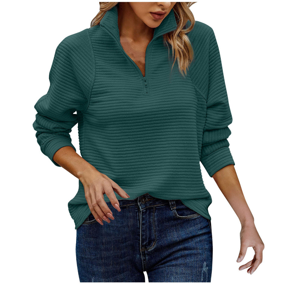 Woman wearing a teal ribbed sweater and jeans on a white background