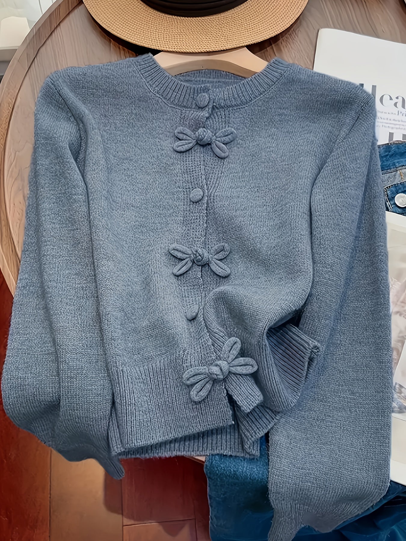 Blue sweater with bow details on a wooden surface
