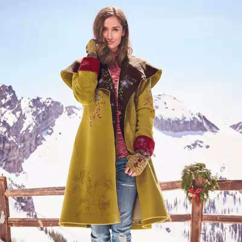 Person wearing a long yellow coat with a mountainous background