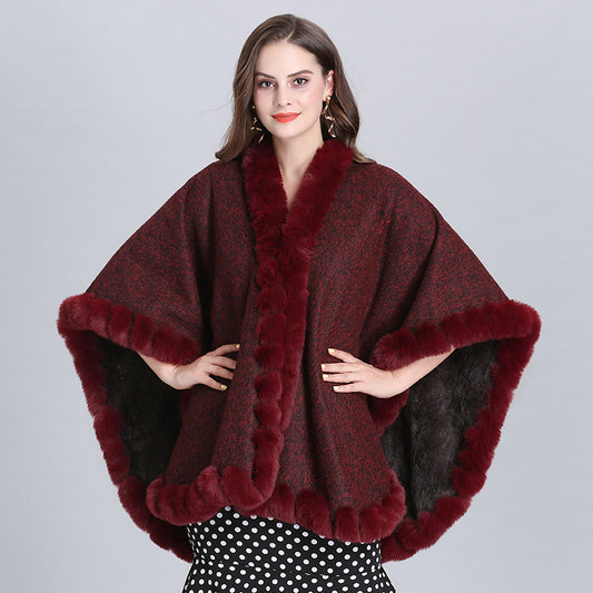 Woman wearing a burgundy poncho with fur trim on a gray background