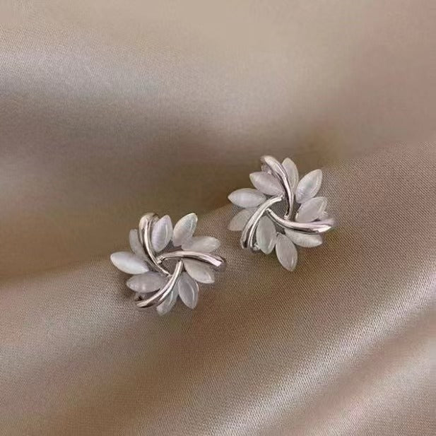 Silver leaf-shaped earrings on a beige fabric background
