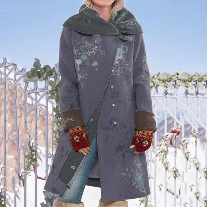 Person wearing a long, dark coat with floral patterns and colorful gloves in a snowy outdoor setting.