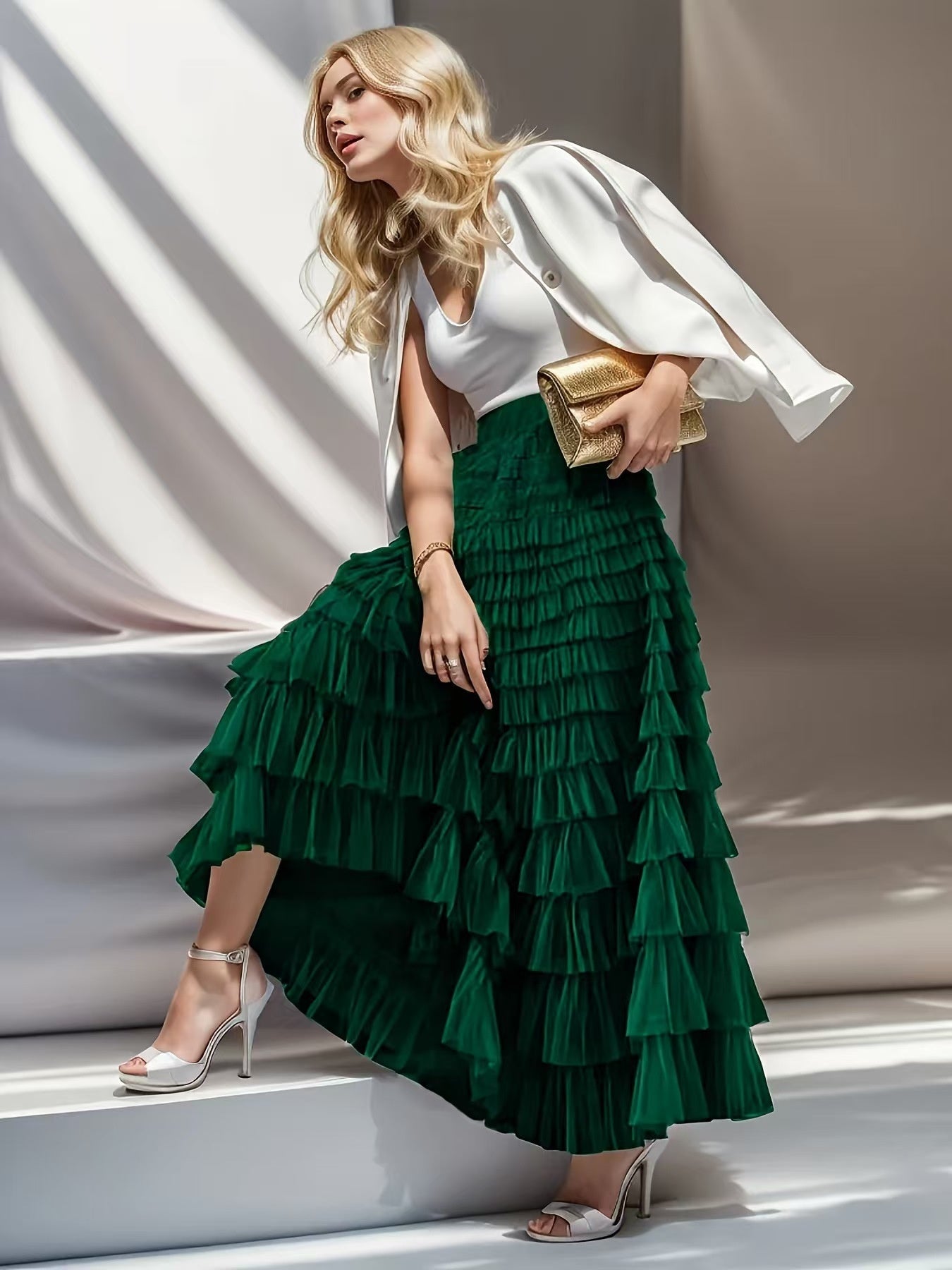 Woman wearing a white top and green ruffled skirt with a gold clutch against a neutral background
