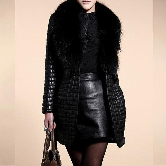 Person wearing a black quilted coat with fur collar and leather skirt on a beige background