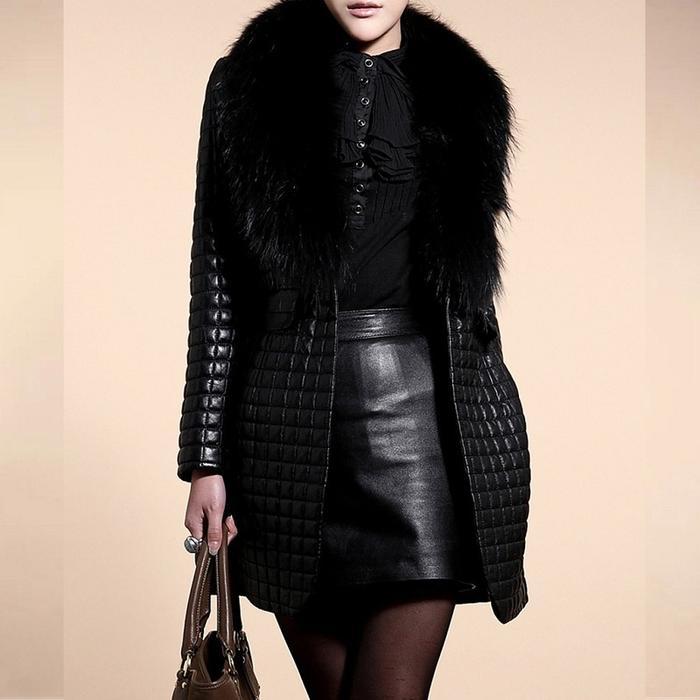 Person wearing a black quilted coat with fur collar and leather skirt on a beige background