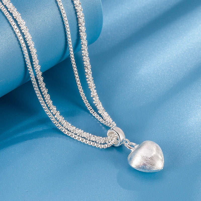 Silver necklace with a heart-shaped pendant on a blue background
