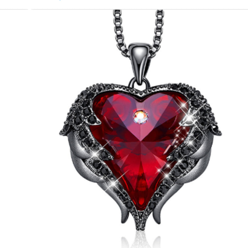 Heart-shaped red gemstone pendant with silver wings on a white background