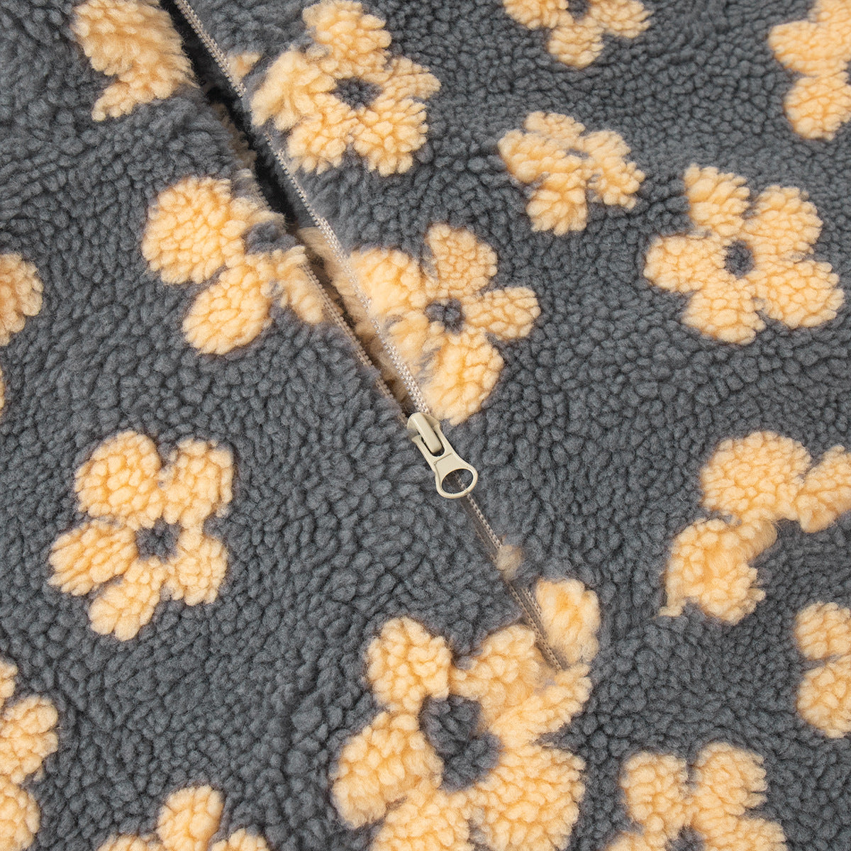 Close-up of a textured fabric with yellow floral patterns and a zipper.