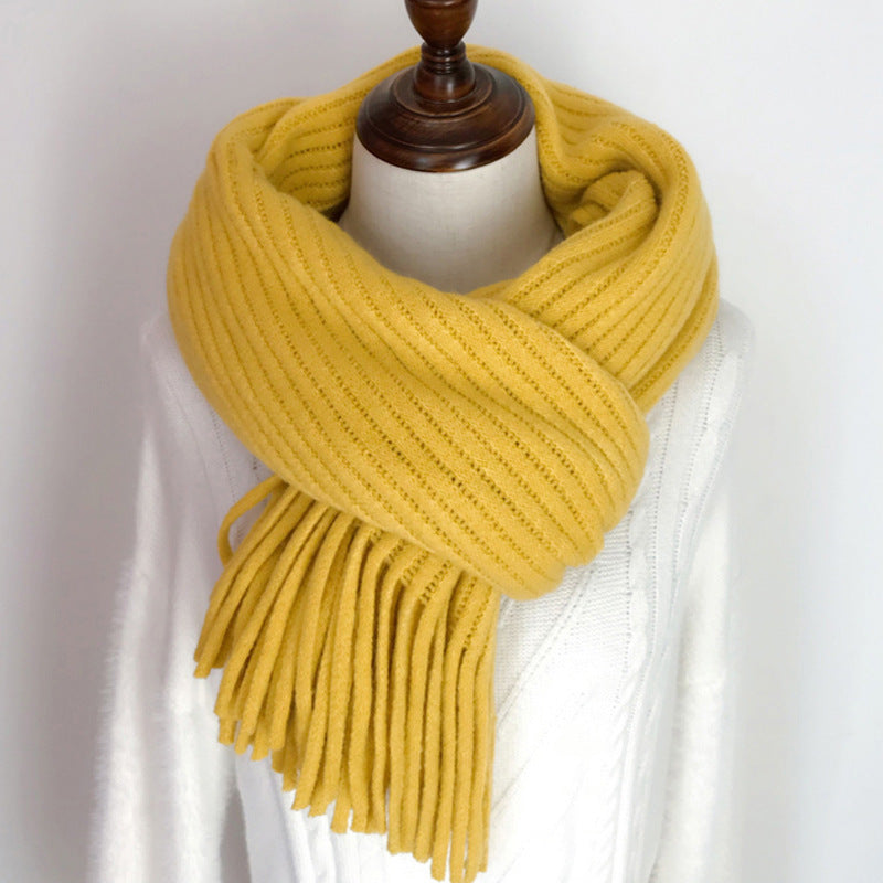 Yellow knitted scarf with fringe on a mannequin against a white background