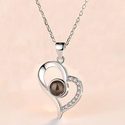 Silver heart-shaped pendant with a brown gemstone on a pink background