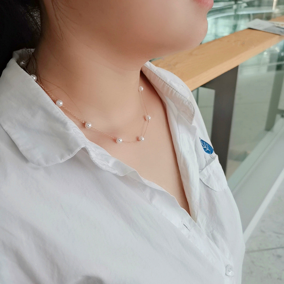 Person wearing a pearl necklace with a white shirt in an indoor setting