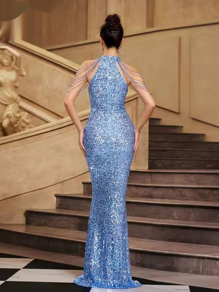 Woman in a blue sequin evening gown standing on a staircase.