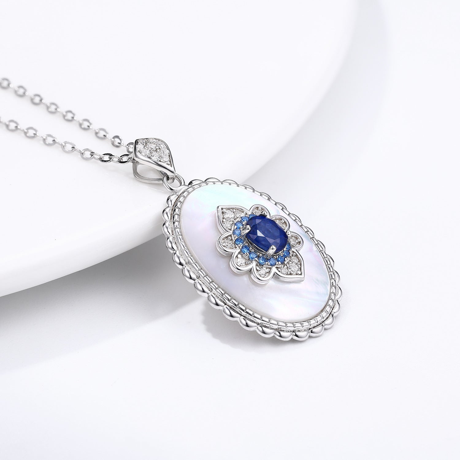 Silver pendant with a blue gemstone on a white background