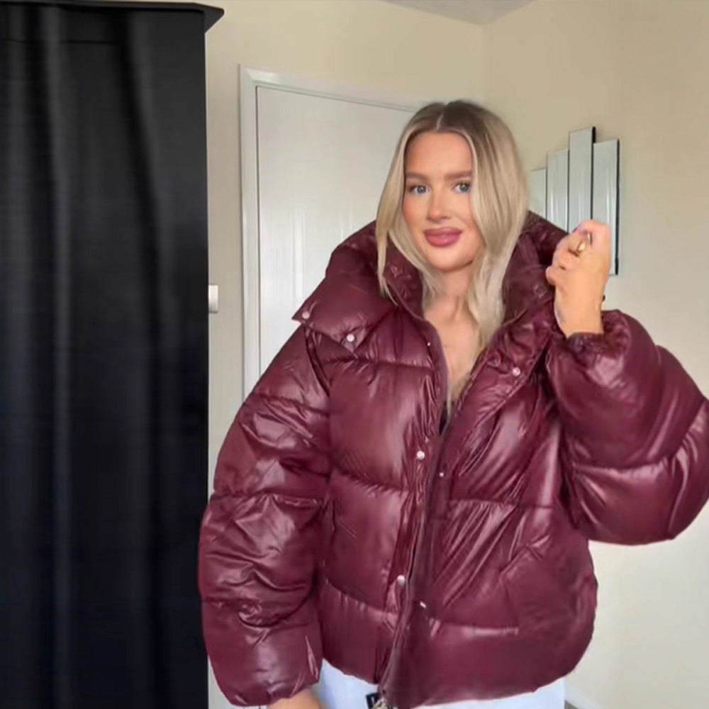 Woman wearing a maroon puffer jacket indoors.